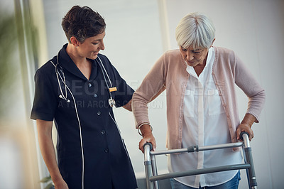 Buy stock photo Cropped shot of a young female nurse assisting a senior woman walk using a walker in a nursing home