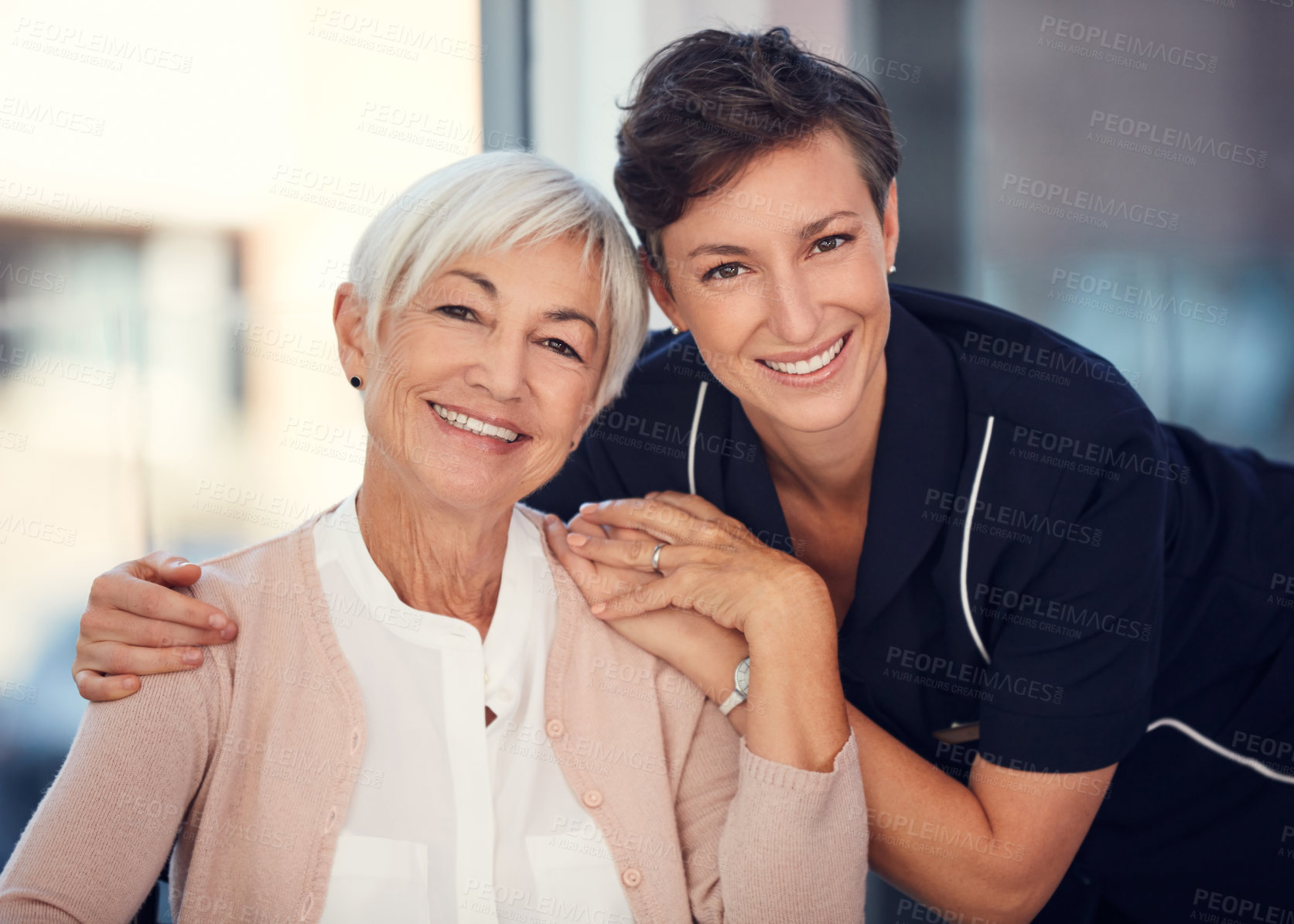 Buy stock photo Cropped portrait of a young female nurse embracing a senior woman sitting in a wheelchair in a nursing home