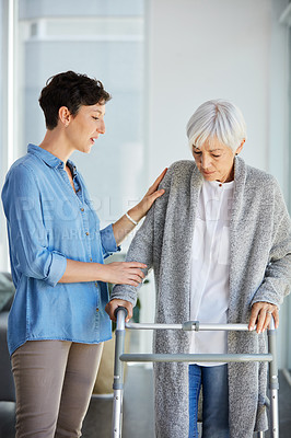 Buy stock photo Cropped shot of an affectionate young woman assisting her aged mother walk using a walker at home