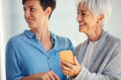 Buy stock photo Cropped shot of a happy senior woman and her daughter looking away while using a smartphone together