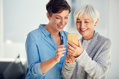 Buy stock photo Cropped shot of an affectionate young woman using a smartphone with her aged mother at home