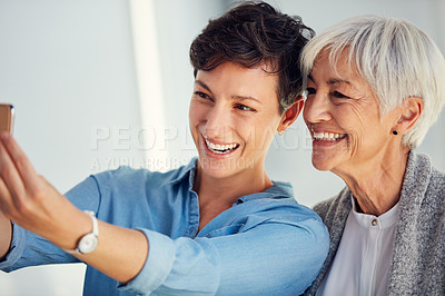 Buy stock photo Cropped shot of an affectionate young woman taking a selfie with her aged mother at home