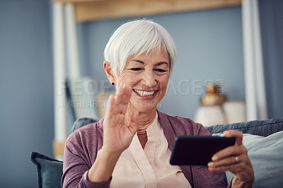Buy stock photo Cropped shot of a happy senior woman waving hello while on a video call on her couch at home