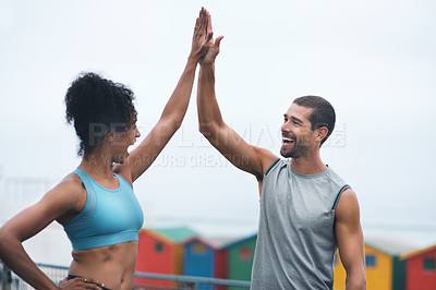 Buy stock photo Shot of two sporty young people giving each other a high five while exercising outdoors