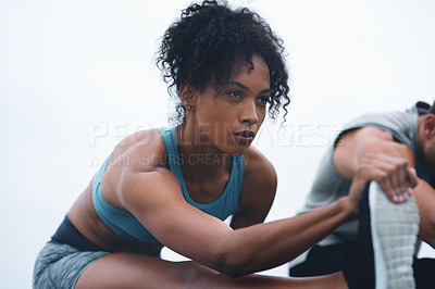 Buy stock photo Shot of a sporty young woman stretching while exercising with her partner outdoors