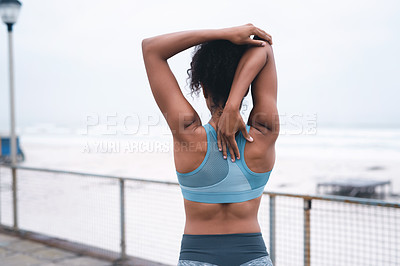 Buy stock photo Rearview shot of a sporty young woman stretching while exercising outdoors