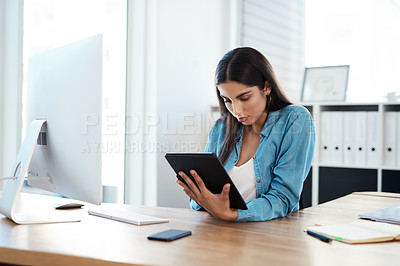 Buy stock photo Shot of a young businesswoman using a digital tablet in an office