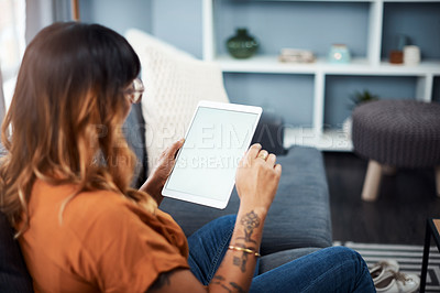 Buy stock photo Shot of a young woman using a digital tablet while relaxing at home