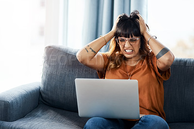 Buy stock photo Shot of a woman looking frustrated while using her laptop at home