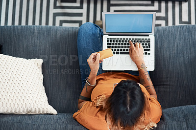 Buy stock photo High angle shot of a young woman holding a credit card while using her laptop