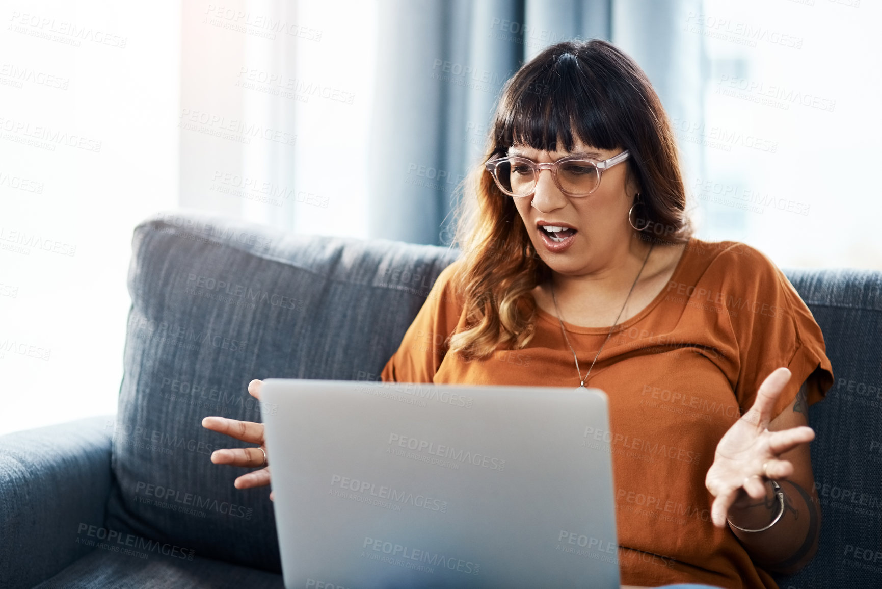 Buy stock photo Shot of a woman looking frustrated while using her laptop at home