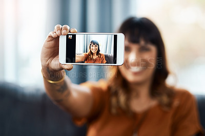 Buy stock photo Cropped shot of a young woman taking selfies while relaxing at home