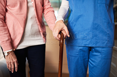 Buy stock photo Shot of a young nurse assisting a senior woman who's walking with a cane