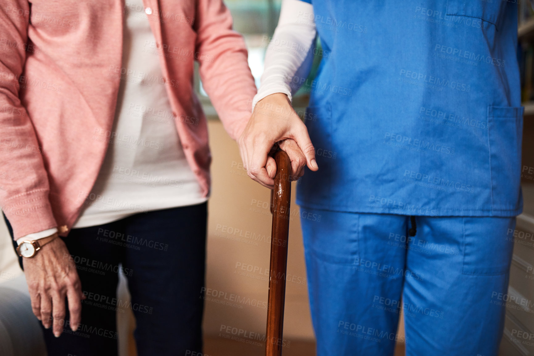 Buy stock photo Shot of a young nurse assisting a senior woman who's walking with a cane