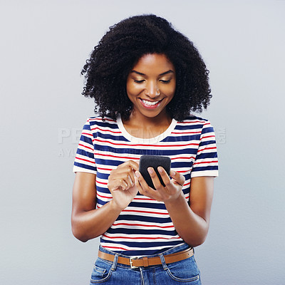 Buy stock photo Studio shot of a beautiful young woman using a smartphone against a grey background