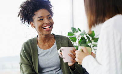 Buy stock photo Cropped shot of two attractive young women sitting together and drinking coffee while at home during the day