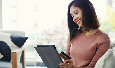 Buy stock photo Cropped shot of an attractive young woman using a tablet for online shopping while sitting on the sofa