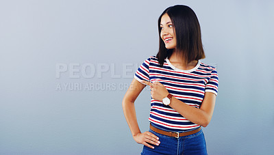 Buy stock photo Studio shot of an attractive young woman pointing at copy space against a grey background