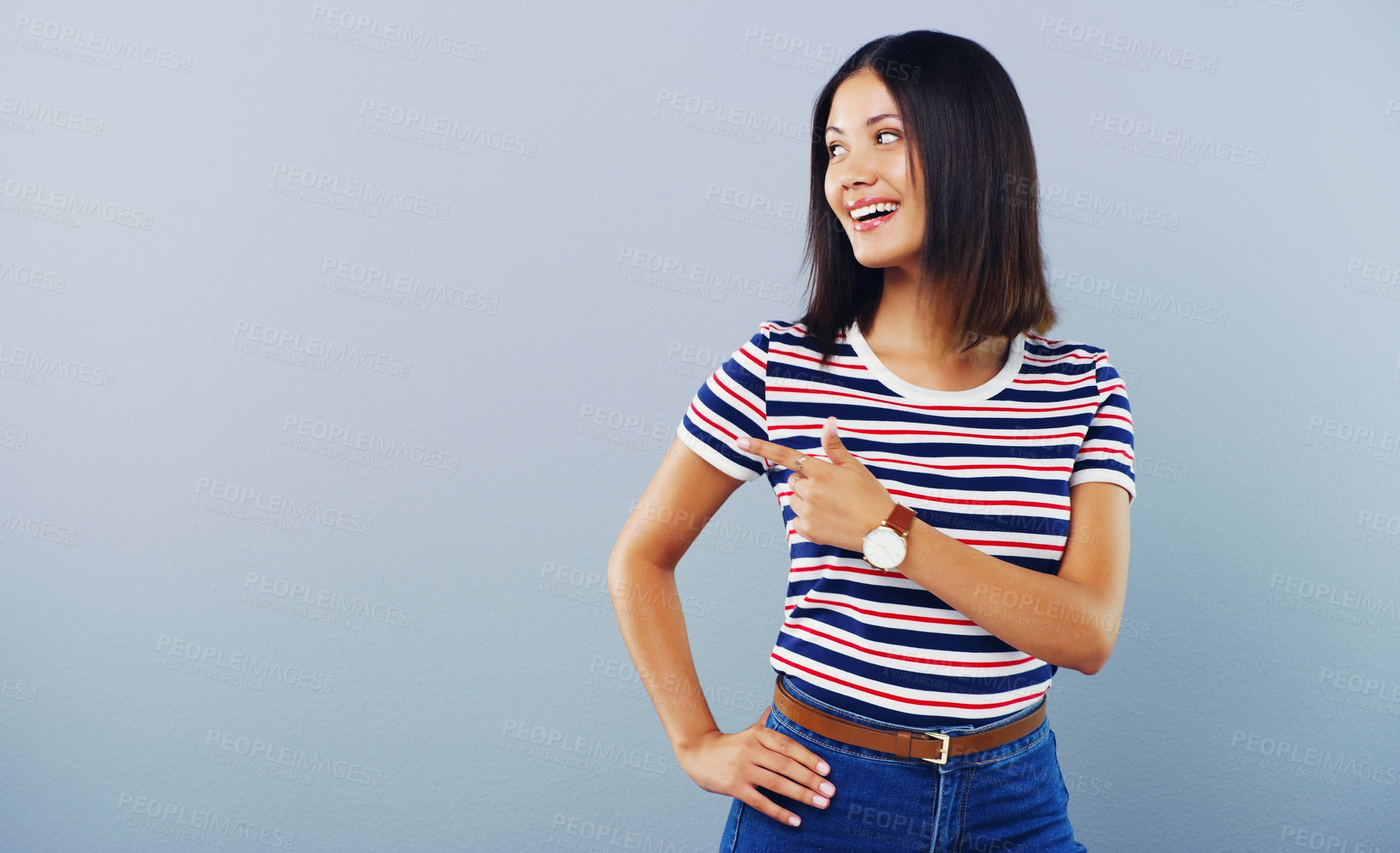 Buy stock photo Studio shot of an attractive young woman pointing at copy space against a grey background