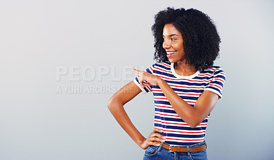 Buy stock photo Studio shot of an attractive young woman pointing at copy space against a grey background