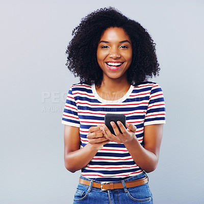 Buy stock photo Studio shot of a beautiful young woman using a smartphone against a grey background