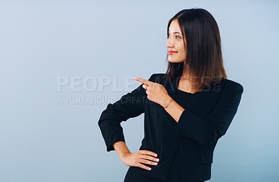 Buy stock photo Studio shot of an attractive young businesswoman pointing at copy space against a grey background