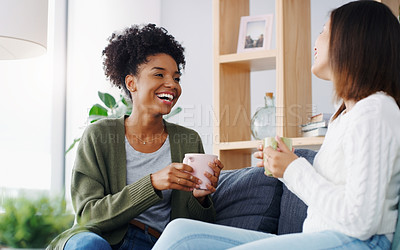 Buy stock photo Cropped shot of two attractive young women sitting together and drinking coffee while at home during the day