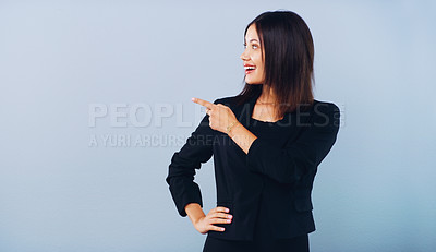 Buy stock photo Studio shot of an attractive young businesswoman pointing at copy space against a grey background
