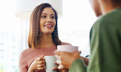 Buy stock photo Cropped shot of two attractive young women sitting together and drinking coffee while at home during the day