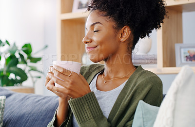 Buy stock photo Cropped shot of an attractive young woman holding a coffee mug while sitting on the sofa in her living room