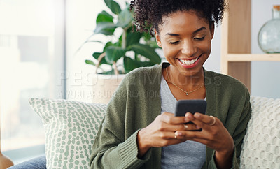 Buy stock photo Cropped shot of an attractive young woman using her cellphone while sitting in the living room during the day