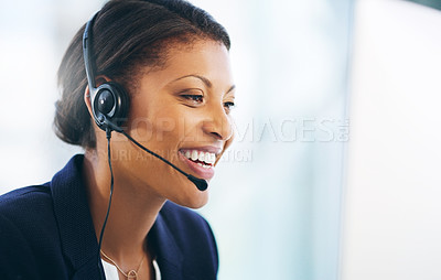 Buy stock photo Shot of a young woman using a headset and computer in a modern office