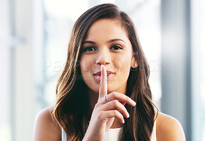 Buy stock photo Portrait of a young businesswoman placing her finger on her lips in a modern office