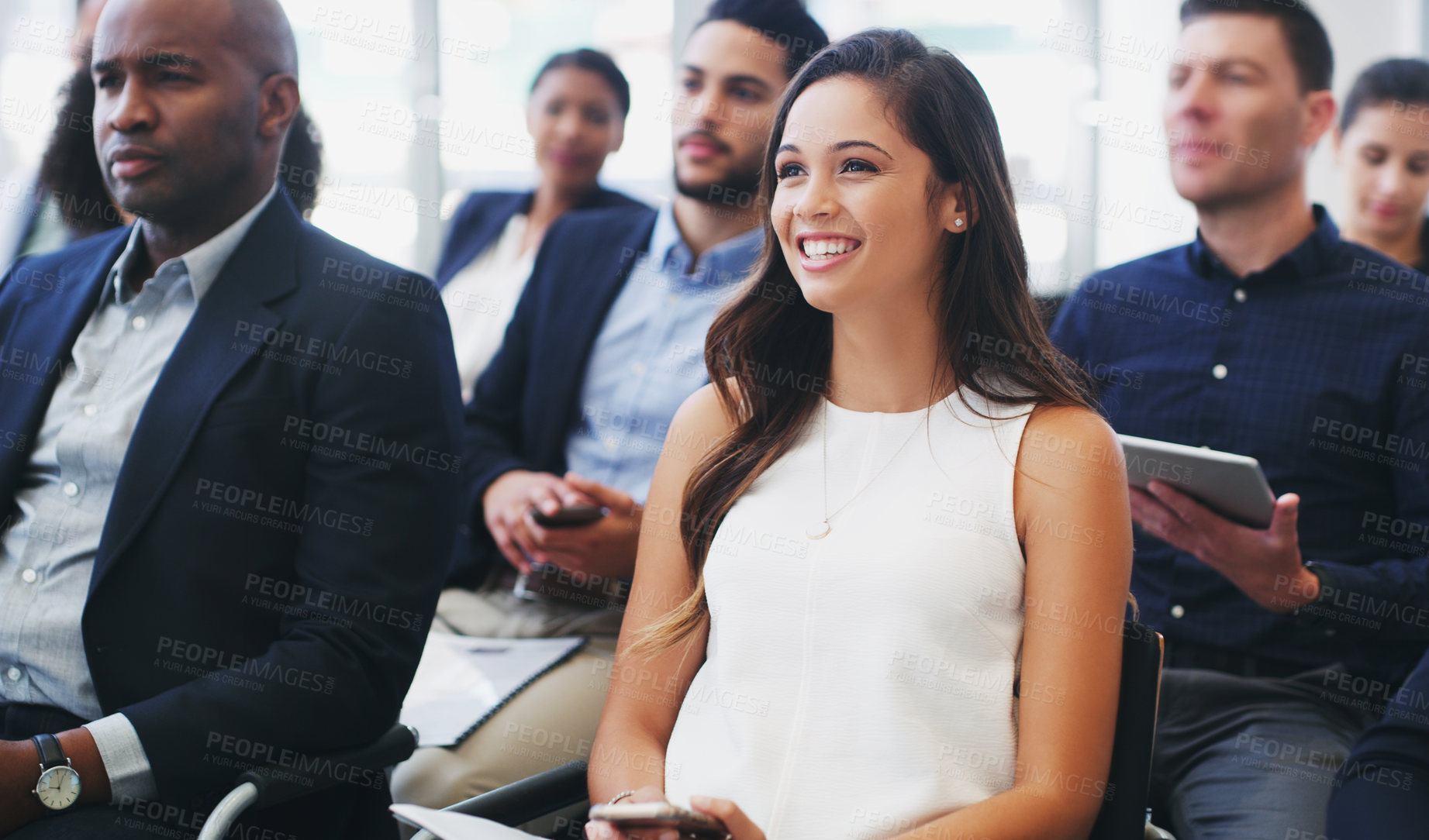 Buy stock photo Shot of a happy young businesswoman sitting in the audience of a business conference