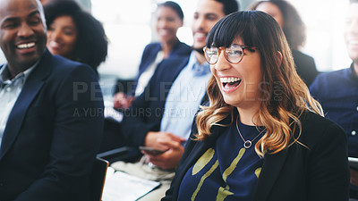 Buy stock photo Shot of a happy young businesswoman sitting in the audience of a business conference and laughing