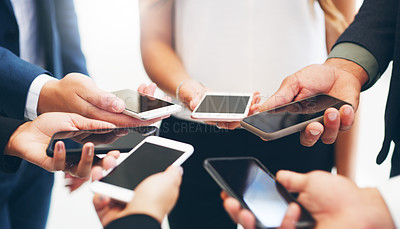 Buy stock photo Cropped shot of a group of businesspeople standing in a circle and using their smartphones in a modern office