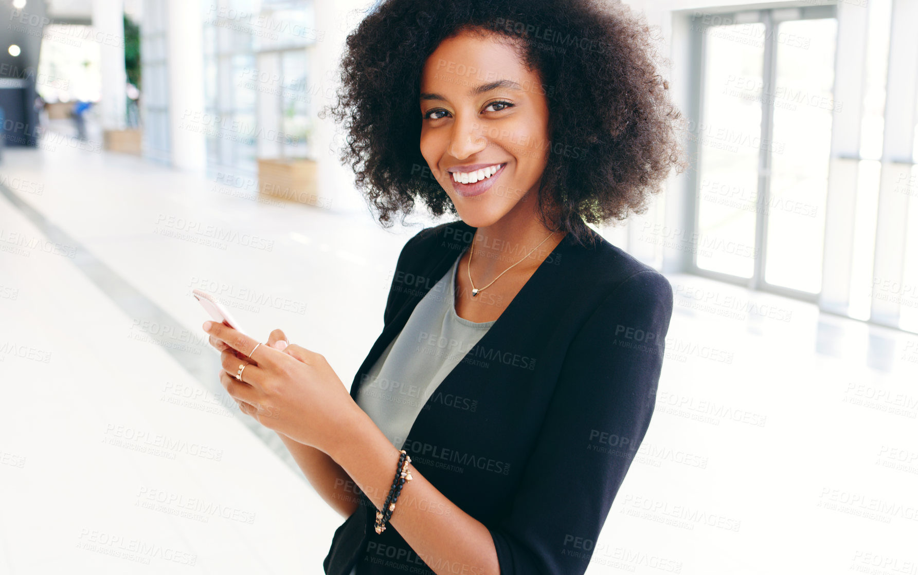 Buy stock photo Shot of a happy young businesswoman using a smartphone in a modern office