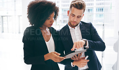 Buy stock photo Shot of a young businessman and businesswoman using a digital tablet during a brainstorming session in a modern office