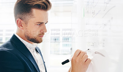 Buy stock photo Shot of a young businessman strategising on a whiteboard in a modern office