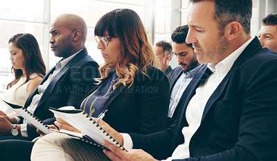 Buy stock photo Shot of a group of businesspeople taking down notes while attending a conference