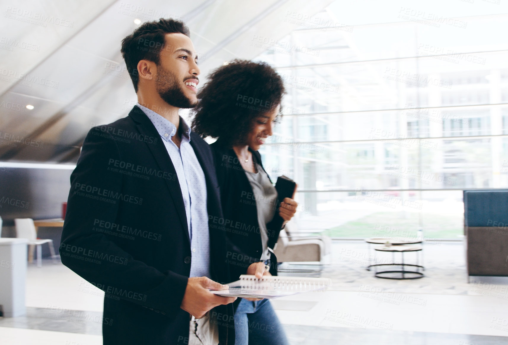 Buy stock photo Shot of a young businessman and businesswoman having a conversation while walking through a modern office