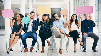 Buy stock photo Shot of a group of businesspeople holding colorful speech bubbles while waiting in line in a modern office
