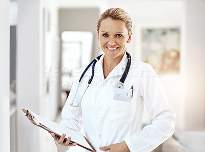 Buy stock photo Cropped portrait of an attractive female doctor standing with her clipboard in the hospital corridor