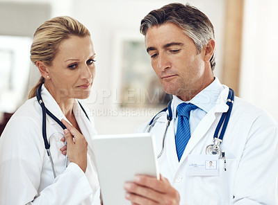 Buy stock photo Cropped shot of two doctors talking together over a digital tablet in the hospital