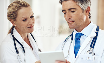 Buy stock photo Cropped shot of two doctors talking together over a digital tablet in the hospital