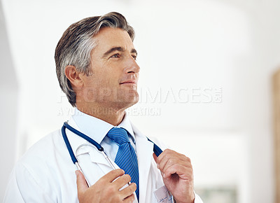 Buy stock photo Cropped shot of a handsome mature male doctor looking thoughtful while standing in the hospital