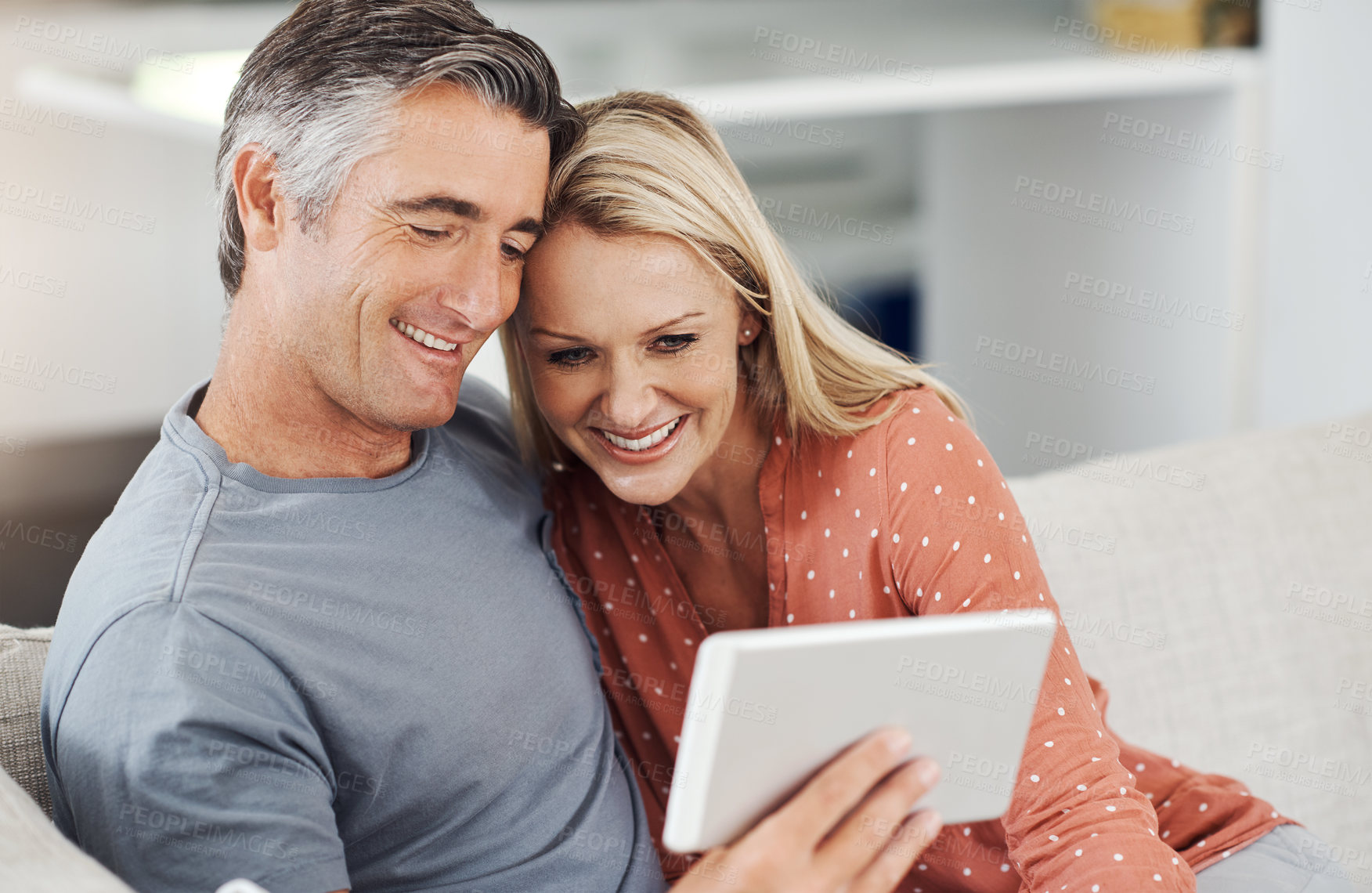 Buy stock photo Mature, couple and happy on tablet in home, relaxing and smile for social media in house. Streaming video, digital platform and website on movie subscription, people and weekend break in apartment