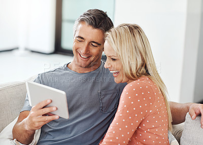 Buy stock photo Cropped shot of an affectionate mature couple relaxing with their digital tablet at home