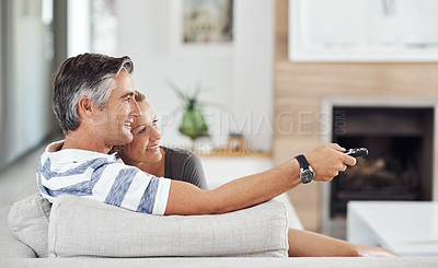 Buy stock photo Cropped shot of an affectionate mature couple cuddling on the sofa while watching movies at home