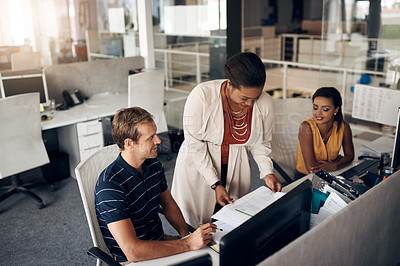 Buy stock photo Cropped shot of a diverse group of businesspeople sitting and looking at paperwork while in a modern office